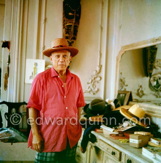 To strike a pose, Pablo Picasso tries on hats from his collection for his own amusement and that of his guests. La Californie, Cannes 1956. - Photo by Edward Quinn