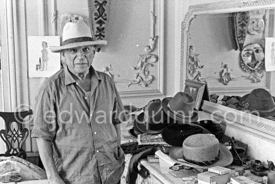 To strike a pose, Pablo Picasso tries on hats from his collection for his own amusement and that of his guests. La Californie, Cannes 1956. - Photo by Edward Quinn