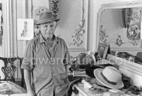 To strike a pose, Pablo Picasso tries on hats from his collection for his own amusement and that of his guests. La Californie, Cannes 1956. - Photo by Edward Quinn