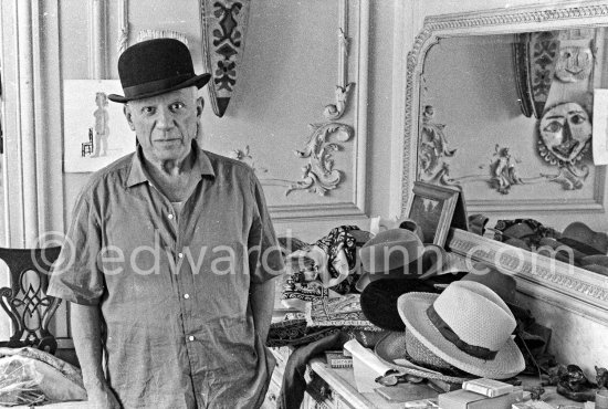 To strike a pose, Pablo Picasso tries on hats from his collection for his own amusement and that of his guests. La Californie, Cannes 1956. - Photo by Edward Quinn