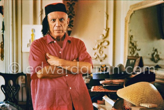 To strike a pose, Pablo Picasso tries on hats from his collection for his own amusement and that of his guests. La Californie, Cannes 1956. - Photo by Edward Quinn
