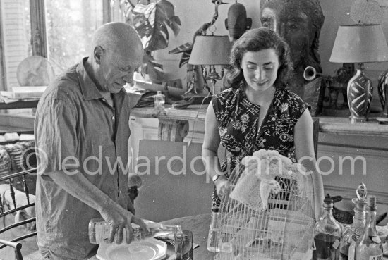 Pablo Picasso and Jacqueline. Luncheon at the dining and work table. Jacqueline is wearing a dress with printed motifs of a Pablo Picasso work. La Californie, Cannes 1956. - Photo by Edward Quinn