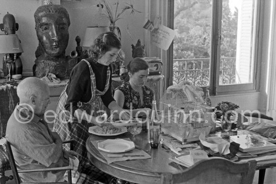 Pablo Picasso, Jacqueline and the cook. Luncheon at the dining and work table. Jacqueline is wearing a dress with printed motifs of a Pablo Picasso work. La Californie, Cannes 1956. - Photo by Edward Quinn