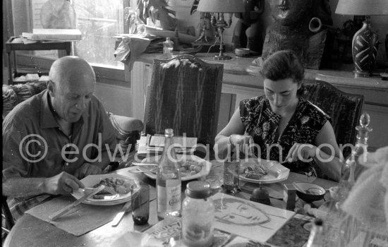 Pablo Picasso and Jacqueline. Luncheon at the dining and work table. Jacqueline is wearing a dress with printed motifs of a Pablo Picasso work. La Californie, Cannes 1956. - Photo by Edward Quinn