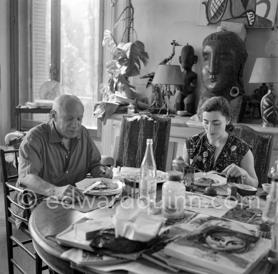 Pablo Picasso and Jacqueline. Luncheon at the dining and work table. Jacqueline is wearing a dress with printed motifs of a Pablo Picasso work. La Californie, Cannes 1956. - Photo by Edward Quinn