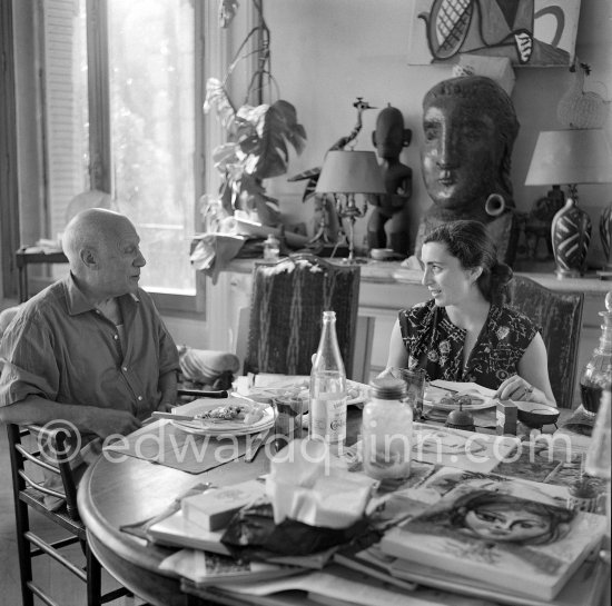 Pablo Picasso and Jacqueline. Luncheon at the dining and work table. Jacqueline is wearing a dress with printed motifs of a Pablo Picasso work. La Californie, Cannes 1956. - Photo by Edward Quinn