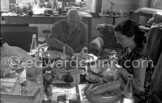 Pablo Picasso and Jacqueline. Luncheon at the dining and work table. Jacqueline is wearing a dress with printed motifs of a Pablo Picasso work. La Californie, Cannes 1956. - Photo by Edward Quinn