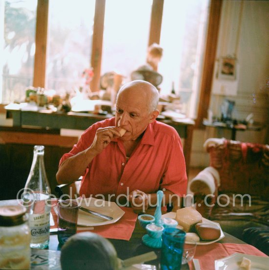 Pablo Picasso and Jacqueline. Luncheon at the dining and work table. Jacqueline is wearing a dress with printed motifs of a Pablo Picasso work. La Californie, Cannes 1956. - Photo by Edward Quinn