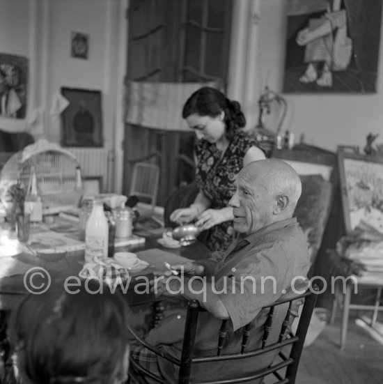 A tea after lunch. Jacqueline and Pablo Picasso at the dining and work table. Jacqueline is wearing a dress with printed motifs of a Pablo Picasso work. La Californie, Cannes 1956. - Photo by Edward Quinn