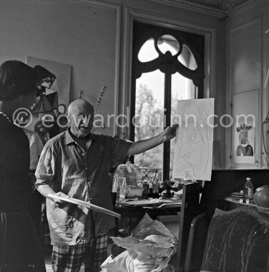 Pablo Picasso shows a drawing he has done of his friend the writer Jacques Prévert. On the left Susi Magnelli. La Californie, Cannes 24.10.1956. (Eve of Pablo Picasso\'s 75th birthday.) - Photo by Edward Quinn