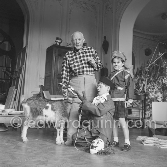 Pablo Picasso with Claude Picasso dressed up as a clown. Paloma Picasso is wearing the Davy Crockett outfit she received as a Christmas present.With goat Esmeralda. La Californie, Cannes 1956. - Photo by Edward Quinn