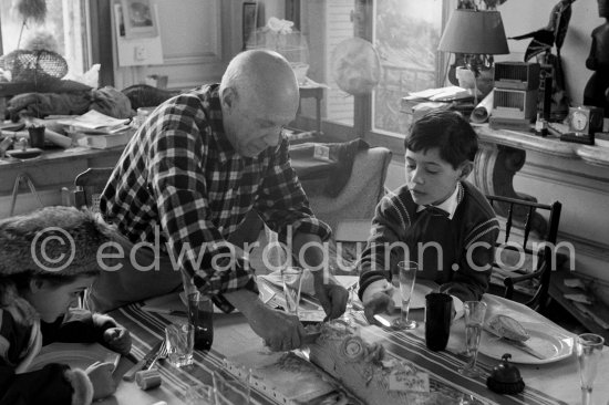 Pablo Picasso cutting the Yule log cake (or bûche de Noël), watched by Paloma Picasso and Claude Picasso. La Californie, Cannes 1956. - Photo by Edward Quinn