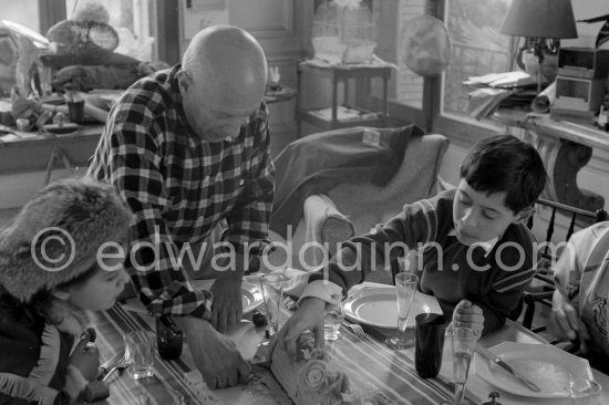 Pablo Picasso, Paloma Picasso and Claude Picasso at Christmas with a Yule log cake (or bûche de Noël). Paloma Picasso is wearing the Davy Crockett outfit she received as a Christmas present. La Californie, Cannes 1956. - Photo by Edward Quinn