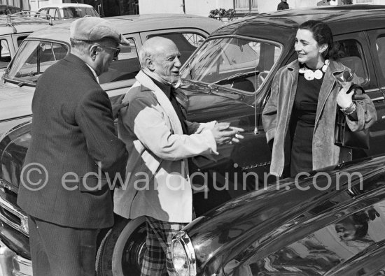 Jaime Sabartés, Jacqueline and Pablo Picasso on Mayday. Jacqueline is holding some sprigs of "muguet", the traditional flower of the day. She's wearing a ceramic necklace made for her by Pablo Picasso. La Croisette, Cannes 1957. - Photo by Edward Quinn