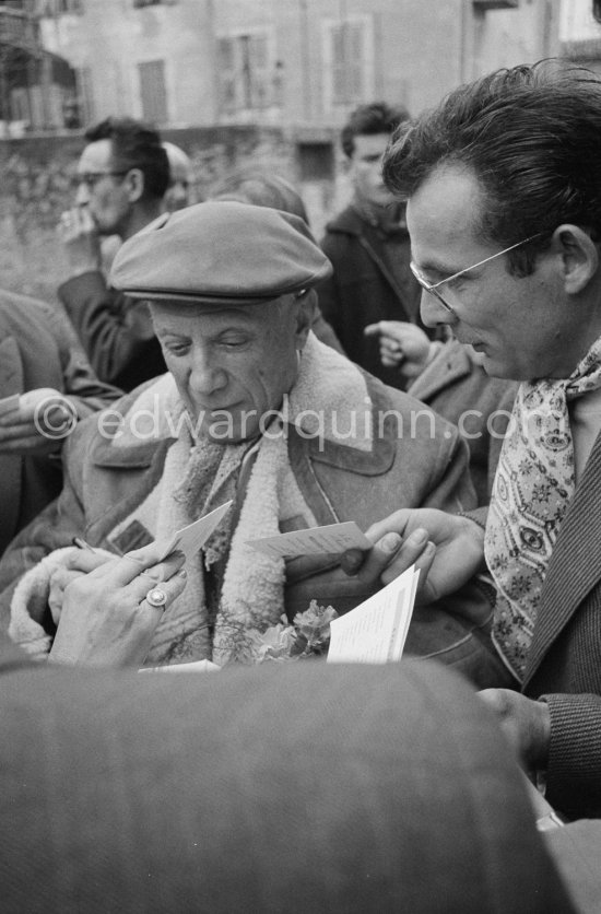 Pablo Picasso signing autograph for Lucien Clergue. Unveiling of mural "The Fall of Icarus" for the conference hall of UNESCO building in Paris. The mural is made up of forty wooden panels. Initially titled "The Forces of Life and the Spirit Triumphing over Evil", the composition was renamed in 1958 by George Salles, who preferred the current title, "The Fall of Icarus". Vallauris, 29 March 1958. - Photo by Edward Quinn
