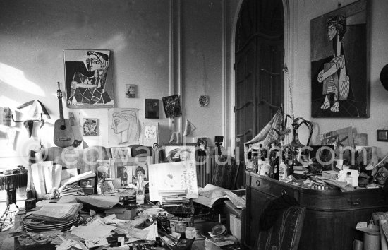 Dining table and sideboard are crowded with a fascinating mixture of objects and papers. On the walls hang two early portraits of Jacqueline dating from 1954. This corner of the living room gives an idea of Pablo Picasso's orderly disorder. La Californie, Cannes 1959. - Photo by Edward Quinn