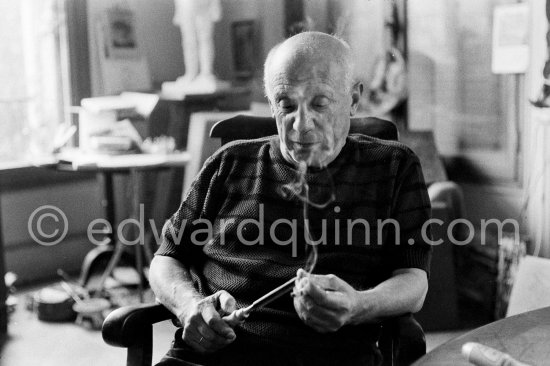 Pablo Picasso feels the sharpness of one of the tools he uses for linocuts. He holds a cigarette at the same time. La Californie, Cannes 1959. - Photo by Edward Quinn