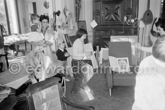 Paloma Picasso pulls a surprise cracker with Catherine Hutin. The Dominguin children and Inès Sassier, Pablo Picasso\'s housekeeper look on. The book open on the armchair shows a portrait of Paloma Picasso. Pablo Picasso, La Californie, Cannes 1959. - Photo by Edward Quinn