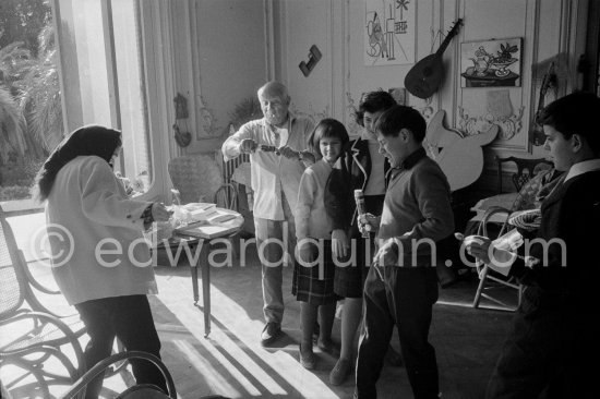 Jacqueline pulls a surprise cracker with Claude Picasso. Behind her daughter Catherine Hutin, Paloma Picasso and Pablo Picasso looking on. On the right Gérard Sassier. La Californie, Cannes 1959. - Photo by Edward Quinn