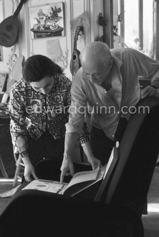Pablo Picasso and Jacqueline viewing a new book with his works. Jacqueline is wearing a blouse made from a textile designed by Pablo Picasso. La Californie, Cannes, 1959. - Photo by Edward Quinn