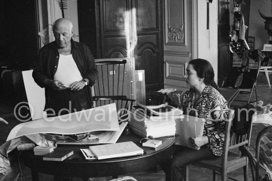 Pablo Picasso correcting "Faunes et chèvres". With Jacqueline (wearing a blouse with Pablo Picasso motifs). A pile of books Level, André: Souvenirs d'un colectionneur. Avec en frontispice un lithographie originale de Pablo Picasso (les saltimbanques). A.C. Mazo, Paris 15.10.1959. La Californie, Cannes 1961. - Photo by Edward Quinn