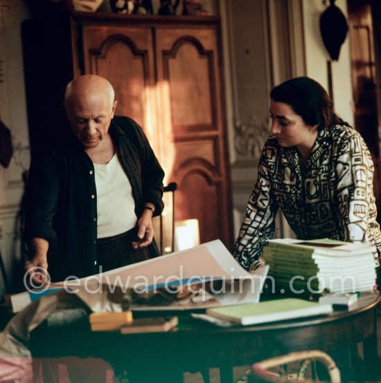 Pablo Picasso correcting "Faunes et chèvres". With Jacqueline (wearing a blouse with Pablo Picasso motifs). A pile of books Level, André: Souvenirs d'un colectionneur. Avec en frontispice un lithographie originale de Pablo Picasso (les saltimbanques). A.C. Mazo, Paris 15.10.1959. La Californie, Cannes 1961. - Photo by Edward Quinn