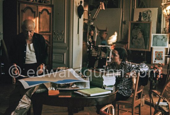 Pablo Picasso correcting "Faunes et chèvres". With Jacqueline (wearing a blouse with Pablo Picasso motifs). A pile of books Level, André: Souvenirs d'un colectionneur. Avec en frontispice un lithographie originale de Pablo Picasso (les saltimbanques). A.C. Mazo, Paris 15.10.1959. La Californie, Cannes 1959. - Photo by Edward Quinn