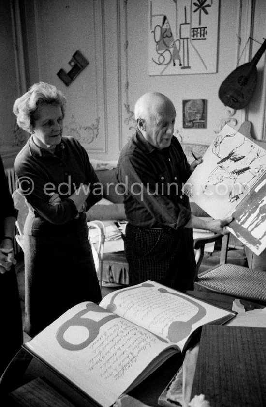 Pablo Picasso shows a sketchbook (drawing 17.7.1959.) and the first copy of a deluxe edition of a book of poems by Pierre Reverdy, for which he has made the illustrations. Louise Leiris, owner with Daniel-Henry Kahnweiler of the Leiris Gallery Paris. La Californie, Cannes 1959. - Photo by Edward Quinn