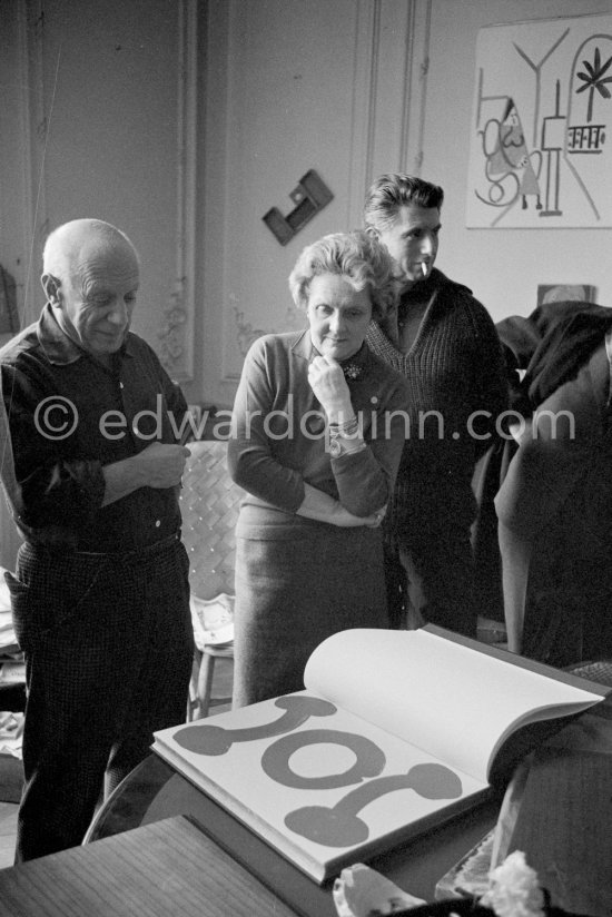 Pablo Picasso looks at the first copy of a deluxe edition of a book of poems by Pierre Reverdy, for which he has made the illustrations. Gathered around him as he comments on the book are Paulo Picasso and Louise Leiris, owner with Daniel-Henry Kahnweiler of the Leiris Gallery Paris. La Californie, Cannes 1959. - Photo by Edward Quinn