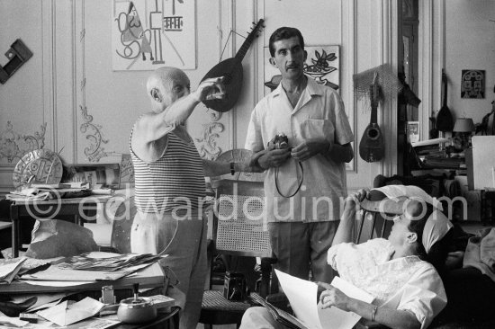 Pablo Picasso, Jacqueline and Edward Quinn viewing photos by Quinn, which the latter brought as a gift. Quinn with his Leica M3, on the chair his Rolleiflex 3.5B. La Californie, Cannes 8.9.1960. Photographer unknown. - Photo by Edward Quinn