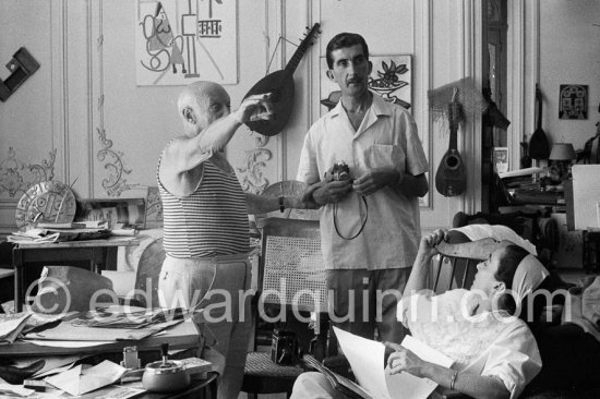 Pablo Picasso, Jacqueline and Edward Quinn viewing photos by Quinn, which the latter brought as a gift. Quinn with his Leica M3, on the chair his Rolleiflex 3.5B. La Californie, Cannes 8.9.1960. Photographer unknown. - Photo by Edward Quinn