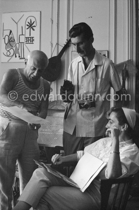 Pablo Picasso, Jacqueline and Edward Quinn discuss a choice of photographs for the book "Pablo Picasso at Work". Quinn with his Leica M3 and Rolleiflex 3.5B. La Californie, Cannes 8.9.1960. Photographer unknown. - Photo by Edward Quinn