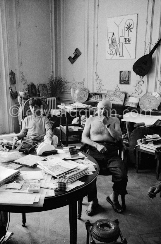 In a corner of his villa Pablo Picasso sits quietly with his son Claude Picasso, on the table a pile of english newspapers reporting on his London exhibition. La Californie, Cannes 1960. - Photo by Edward Quinn