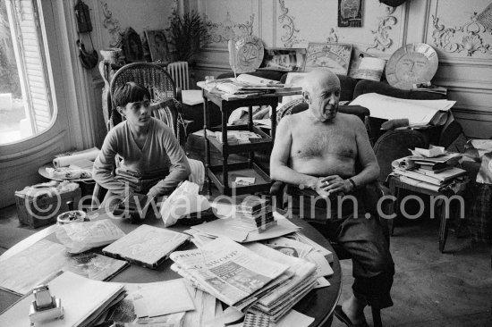 In a corner of his villa Pablo Picasso sits quietly with his son Claude Picasso, on the table a pile of English newspapers reporting on his London exhibition. La Californie, Cannes 1960. - Photo by Edward Quinn