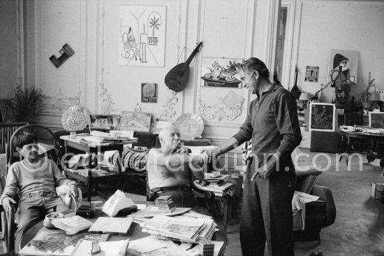 Pablo Picasso, photographer David Douglas Duncan and Claude Picasso. On the table a pile of english newspapers reporting on Pablo Picasso\'s London exhibition. La Californie, Cannes 1960. - Photo by Edward Quinn