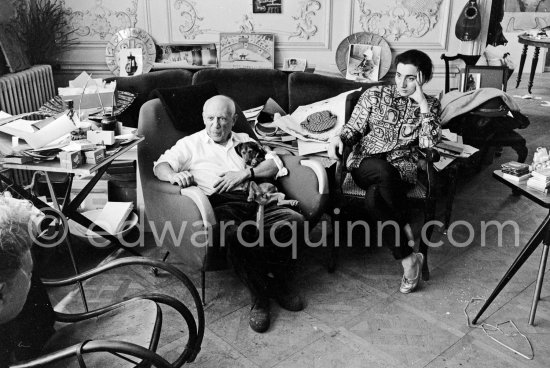Pablo Picasso and Jacqueline (she is wearing a blouse made from a textile designed by Pablo Picasso) with dachshund Ma Jolie. A table by Joseph-Marius Tiola on the left. La Californie, Cannes 1961. - Photo by Edward Quinn