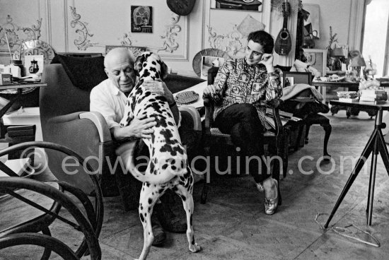 As Jacqueline watches, Pablo Picasso gets an affectionate visit from Perro. Jacqueline is wearing a blouse made from a textile designed by Pablo Picasso. La Californie, Cannes 1961. - Photo by Edward Quinn