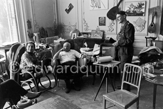 Pablo Picasso and Jacqueline and unidentified soldier. Jacqueline, sitting in a rocking chair, is wearing a blouse made from a textile designed by Pablo Picasso. La Californie, Cannes 1961. - Photo by Edward Quinn