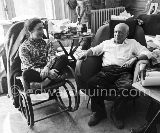 Pablo Picasso and Jacqueline. Jacqueline, sitting in a rocking chair, is wearing a blouse made from a textile designed by Pablo Picasso. La Californie, Cannes 1961. - Photo by Edward Quinn