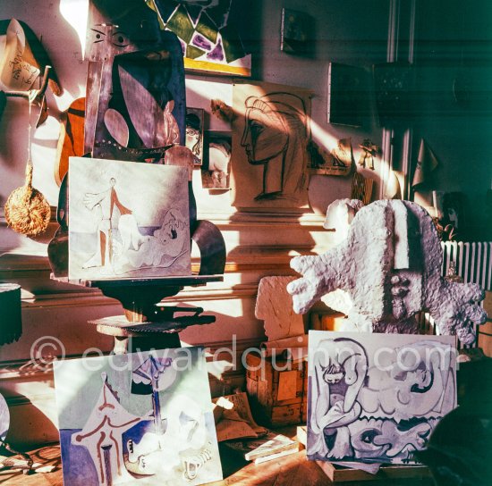 The proverbial disorder of the rooms in which Pablo Picasso works is unique. Beside the large pieces of sculpture in painted iron and plaster hang portraits of Jacqueline and Paloma Picasso surrounded by drawings, objects and notes pinned to the wall. La Californie, Cannes 1961. - Photo by Edward Quinn