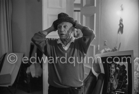 To strike a pose, Pablo Picasso tries on hats from his collection for his own amusement and that of his guests. Mas Notre-Dame-de-Vie, Mougins 1964. - Photo by Edward Quinn