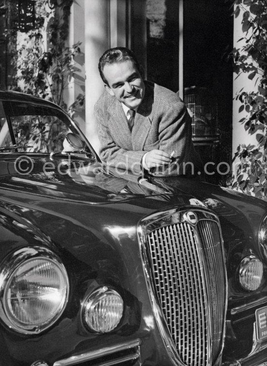 Car enthusiast Prince Rainier of Monaco at his Villa Iberia. He competed under the pseudonym of Louis Carladès at the Tour de France de l\'automobile and crashed into a tree. Saint-Jean-Cap-Ferrat 1954. Car: Lancia Aurelia B20 Gran Turismo 2500 - Photo by Edward Quinn