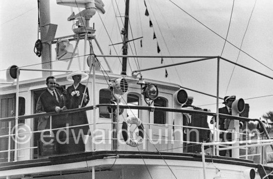 Grace Kelly and Prince Rainier on his yacht Deo Juvante II. She came ashore from the liner S.S. Constitution, which brought her to Monaco for her marriage. Monaco 1956..She wore a matching navy blue silk dress and coat by Ben Zuckerman of New York with a fashonable but troublesome wide-brimmed hat. - Photo by Edward Quinn