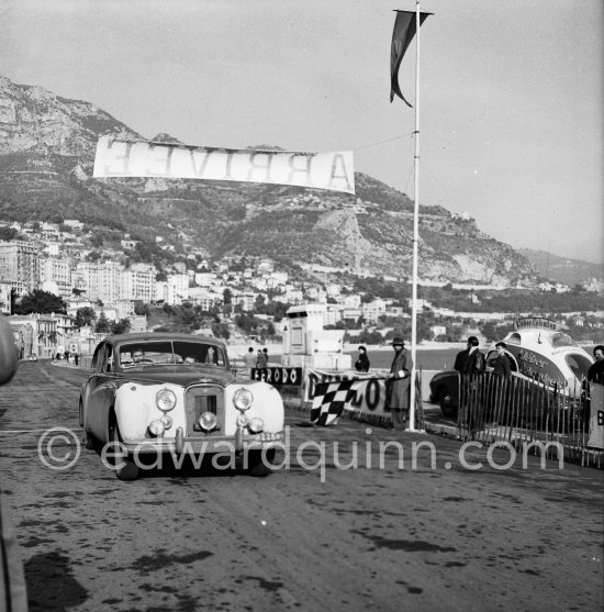 N° 228 E. I. Appleyard and Mrs. P.C. Appleyard on Jaguar MK VII on arrival at Monte Carlo beach after Col de Braus regularity test. Monte Carlo Rally 1953. To prevent the competitors from taking the timekeepers by surprise and passing without being spotted the organisers decided to paint the front wings of the cars white with washable paint. This enabled the officials to identify them a long way off even if their rally plates were not easily visible because of dirt or their position on the car. (Louche p. 118) - Photo by Edward Quinn