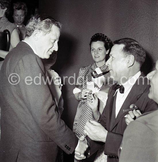 Jules Dassin, American film and theatre director, producer, writer and actor, greeting Georges Simenon. Simenon's wife in the background. Cannes Film Festival 1955 - Photo by Edward Quinn