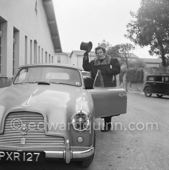 A top-head salute of Peter Ustinov at the Studios de la Victorine during filming of "Lola Montès". Nice 1955. Car: 1955 Aston Martin DB 2/4 Drophead coupé - Photo by Edward Quinn