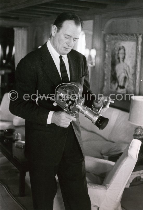 John Wayne checking out a Pathé film camera on board Onassis\' yacht Christina, Monaco harbor 1955. - Photo by Edward Quinn