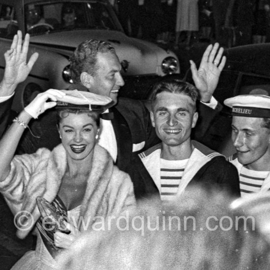 Esther Williams posing with French sailors at the entrance to the Palais du Festival Cannes 1955. Behind her waving to the crowds is her husband, Benjamin Gage. - Photo by Edward Quinn