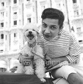 Princess Ashraf, sister of the Shah of Persia, blouse and wallet matching, posing in front of Carlton Hotel with her poodle. Cannes 1953. - Photo by Edward Quinn