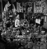 Louis Chiron at his museum of the victories: This photo on which are grouped the trophies of Chiron, summarizes thirty years of racing. One sees cups of Alfonso XIII., the Queen of England, the president of the Spanish Republic, Mussolini, the King of Italy, the Sultan of Morocco. The Count of Paris dedicated a photo "A Chiron the Centaur" to him. Monaco 1954. - Photo by Edward Quinn